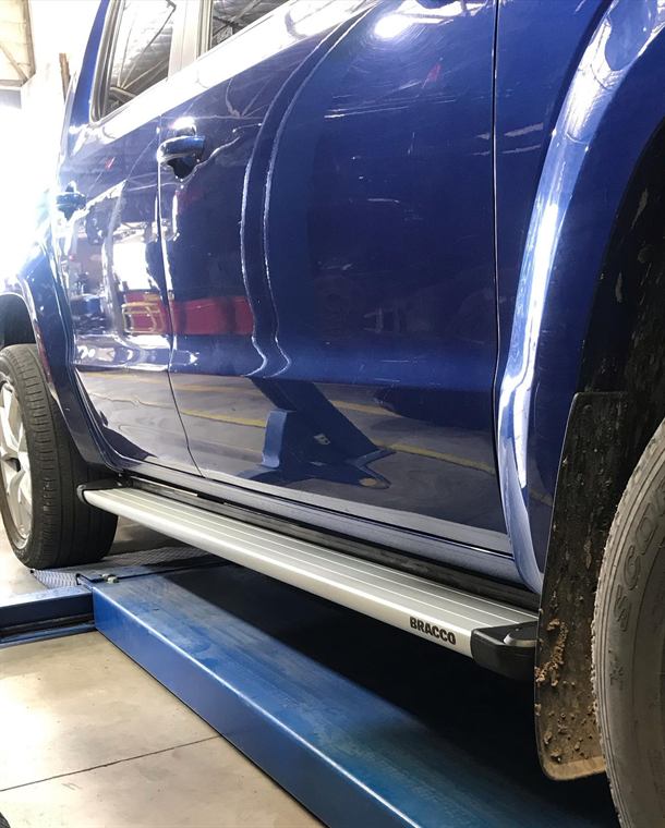 Estribos laterales instalados en una camioneta azul