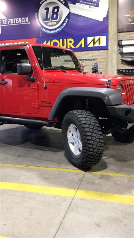 Jeep Wrangler rojo con neumáticos todo terreno en el taller